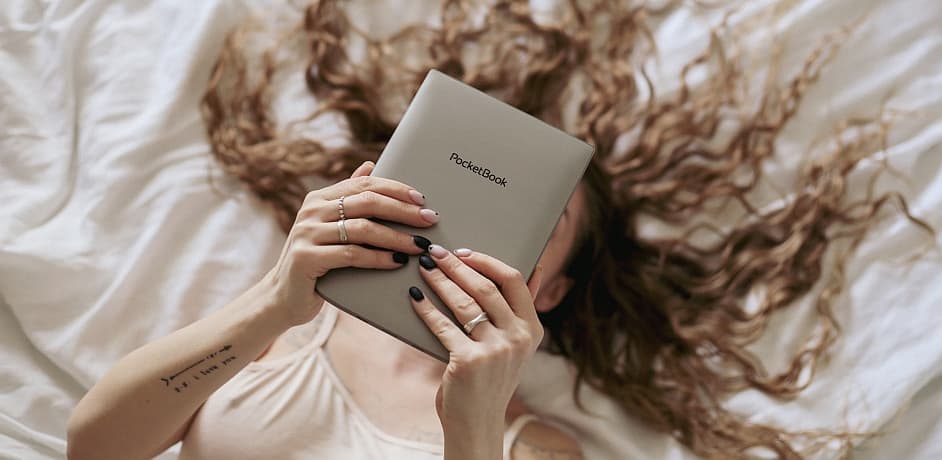 Eine Frau liegt im Bett und liest auf einem PocketBook E-Reader. Ihr Gesicht ist durch das Gerät verdeckt. Eine Frau liegt im Bett und liest auf einem PocketBook E-Reader. Ihr Gesicht ist durch das Gerät verdeckt.